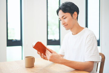 自宅のリビングで読書をする若い男性