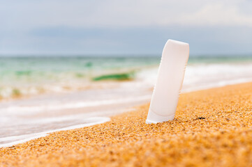 Bottle of sunscreen on the beach. sunburn lotion on the beach with the sparkling sea in the background and rolling waves. Close up of sunscreen cosmetic products