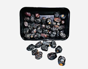 A pile of black Ajwa dates on a white background 