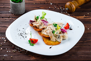 Potato pancakes with chicken fillet and mushrooms in cream sauce, tomatoes and lettuce.