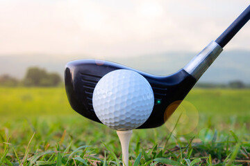 A golf ball is placed on the grass with a mountain view behind.