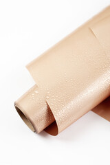 Glossy nude wrapping paper for gifts or flowers with drops of water on white background. Top view