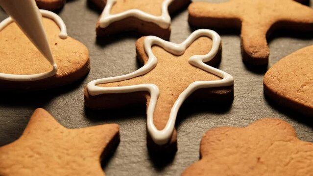 Decoration of homemade gingerbread man with food icing glaze. Christmas Gingerbread cookies. Sweet food. New year food concept. Close-up in 4K, UHD