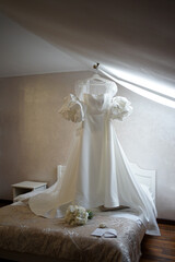 A beautiful white wedding dress hangs in the room. Preparation for the wedding ceremony.