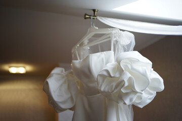 A beautiful white wedding dress hangs in the room. Preparation for the wedding ceremony.