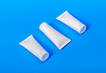 Face cream, mask, scrub, gel tubes mockup row, three cosmetic product packages, blank white containers