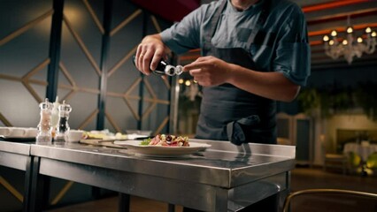 A chef holds a bottle of balsamic vinegar and dresses a bruschetta with it in the kitchen of an Italian restaurant