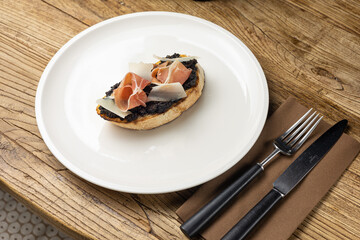 Tasty bruschetta with jamon and cheese on a wooden table