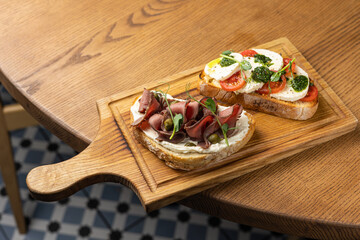 Tasty bruschetta with jamon and cheese on a wooden table