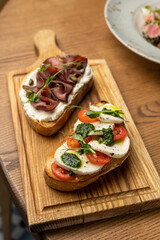Tasty bruschetta with jamon and cheese on a wooden table