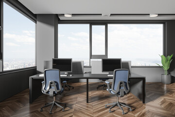 Grey office workspace interior with pc computers and table near panoramic window