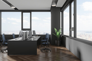 Grey coworking interior with pc computers and desk near panoramic window