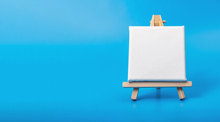 Blank empty canvas on easel, blue banner background