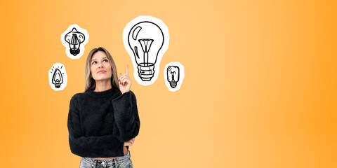 Young pensive woman and set of lightbulbs on copy space orange background
