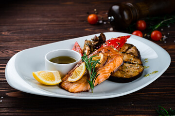 Grilled salmon fillet with eggplant, zucchini, mushrooms, sweet peppers, lemon, rosemary and sauce, fresh lunch.