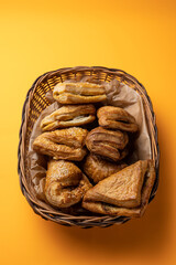 Tasty pastries in a basket on an orange background
