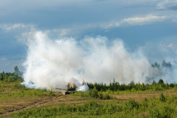 Heavy combat vehicles tanks drive around the butts and put up a smoke screen