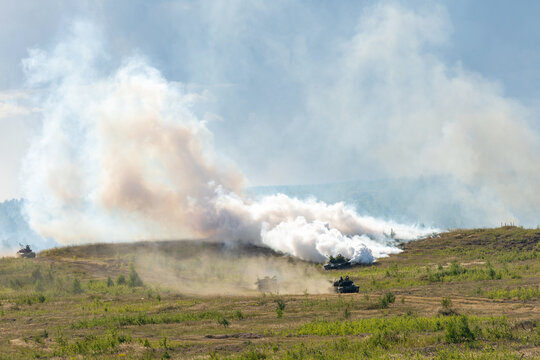 Heavy combat vehicles tanks drive around the butts and put up a smoke screen