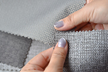 Close up view, Human hand selecting fabrics material samples for making furniture and home...