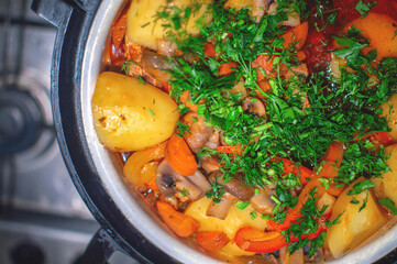 Homemade stew with potatoes and carrots in tomato sauce. A homemade dish in a pot stands on a gas...