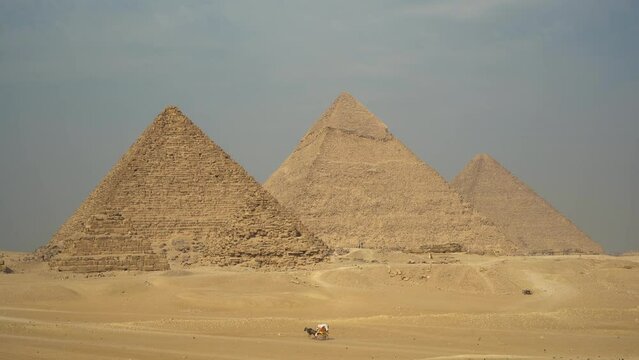 Ancient pyramids with tourists in the hot African desert on a sunny day