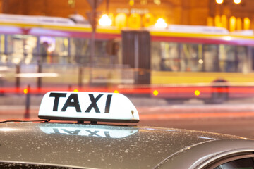 Shining Taxi inscription close up against passing cars on night street of big citi