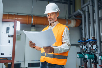 Refinery supervisor checking blueprints logistics of gas distribution.