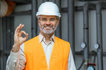 old caucasian man wearing contractor uniform and safety helmet happy with big smile doing ok sign