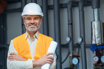 senior gray haired Happy Smiling Professional Engineer Worker Wearing Uniform, and Hard Hat in boiler room.