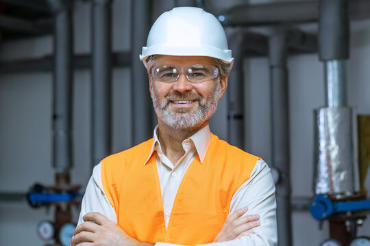 senior gray haired Engineer Manufacture Worker. Caucasian man in Hard Hat and Safety Wear. Confident Older Attractive Mechanic of Machine Inspection for Machinery Tool Job Indoors