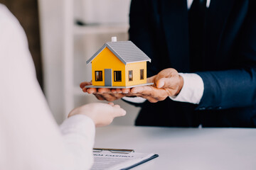 Accountant, businessman, real estate agent, Asian business woman handing keys to customers along with house after customers to sign