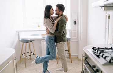 Loving couple hugging and kissing in kitchen during romantic weekend
