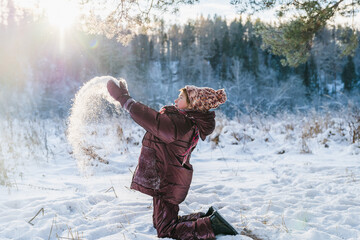 cute girl in the forest in winter throws snow