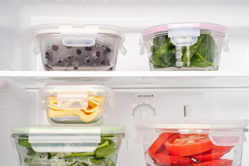 Vegetables and berries in glass boxes in the refrigerator close-up.