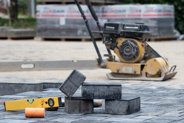 Construction site with paving slabs, a level and a construction machine - obrazy, fototapety, plakaty