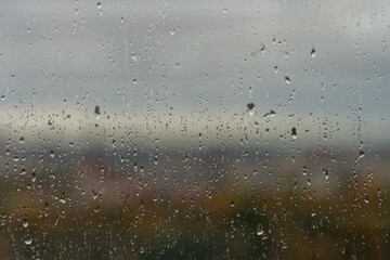 Bad weather. Dark clouds seen through raindrops on the window on a rainy day