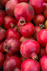 Background pattern of pomegranate garnet fruit. Whole pomegranate with flower. Texture background of the pile of fresh raw organic garnet fruit. Top view of the pile of natural ruby pomegranate