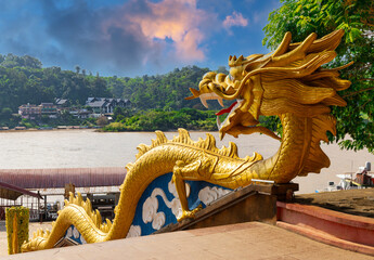 Golden Dragon with wide open mouth wrapped down the Stairs at the Golden Triangle on the Laos Side facing Thailand and Myanmar  - obrazy, fototapety, plakaty