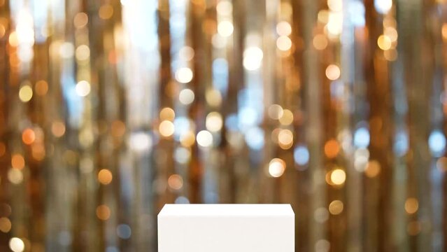 Product presentation scene made with white pedestal and blurred bokeh festive background made with foil fringe curtainbackground. Front view footage. 