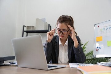 Business asian women are stress while working on laptop, Tired business woman with headache at...