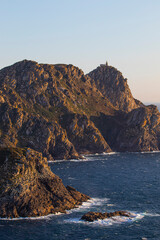 Part of an island in northern Spain illuminated in the evening light with a lighthouse on top
