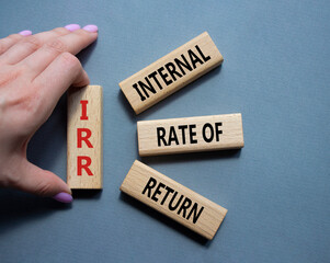 IRR - Internal Rate of Return symbol. Concept word IRR on wooden cubes. Businessman hand. Beautiful grey background. Business and IRR concept. Copy space.