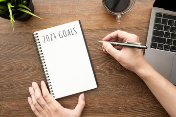 Man is writing 2024 goals for new year resolutions plan.