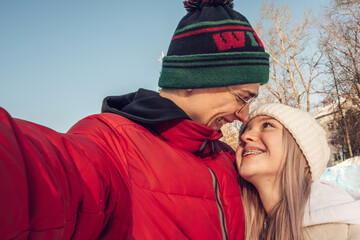 Portrait of a couple of happy teenagers taking photo of yourself, selfie,on a winter day at an outdoor skating rink.Winter entertainment,leisure activity,Valentine's day,generation Z.