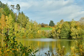 La beauté bucolique des feuillage vert-dorés des arbres se reflétant dans les eaux de l'étang au domaine du château de la Hulpe 