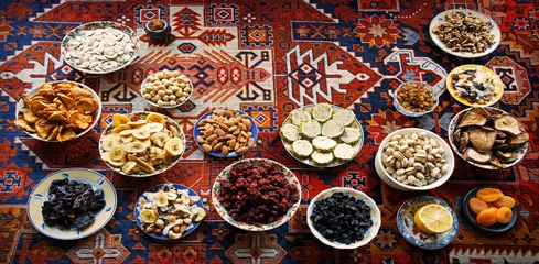 Schilderijen op glas Eastern feast. Asian still life of dried fruits and nuts in plates on a carpet © Marina