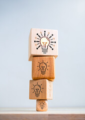 Think big. Inspiration, innovative technology, goal and success concepts. Biggest modern idea lightbulb icon on top of bulbs symbol on smaller wooden cube blocks stack isolated on white background. - obrazy, fototapety, plakaty