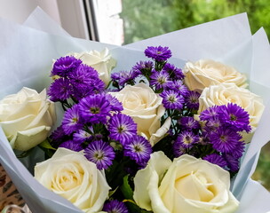 Bouquet of flowers of white roses and lilac asters close-up