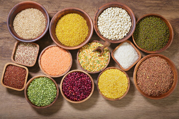 bowls of legumes, lentils, chickpeas, rice and beans on wooden background