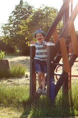Funny little boy posing and smiling on wooden playhouse steps. A lovely and wonderful warm summer...